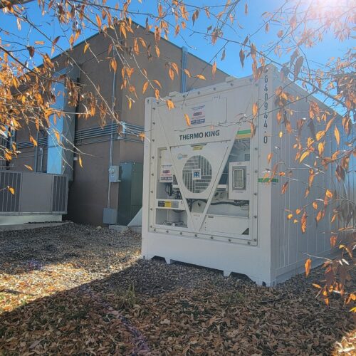 A reefer container behind a building in the fall, one of many refrigerated containers sold or rented by USA-Containers